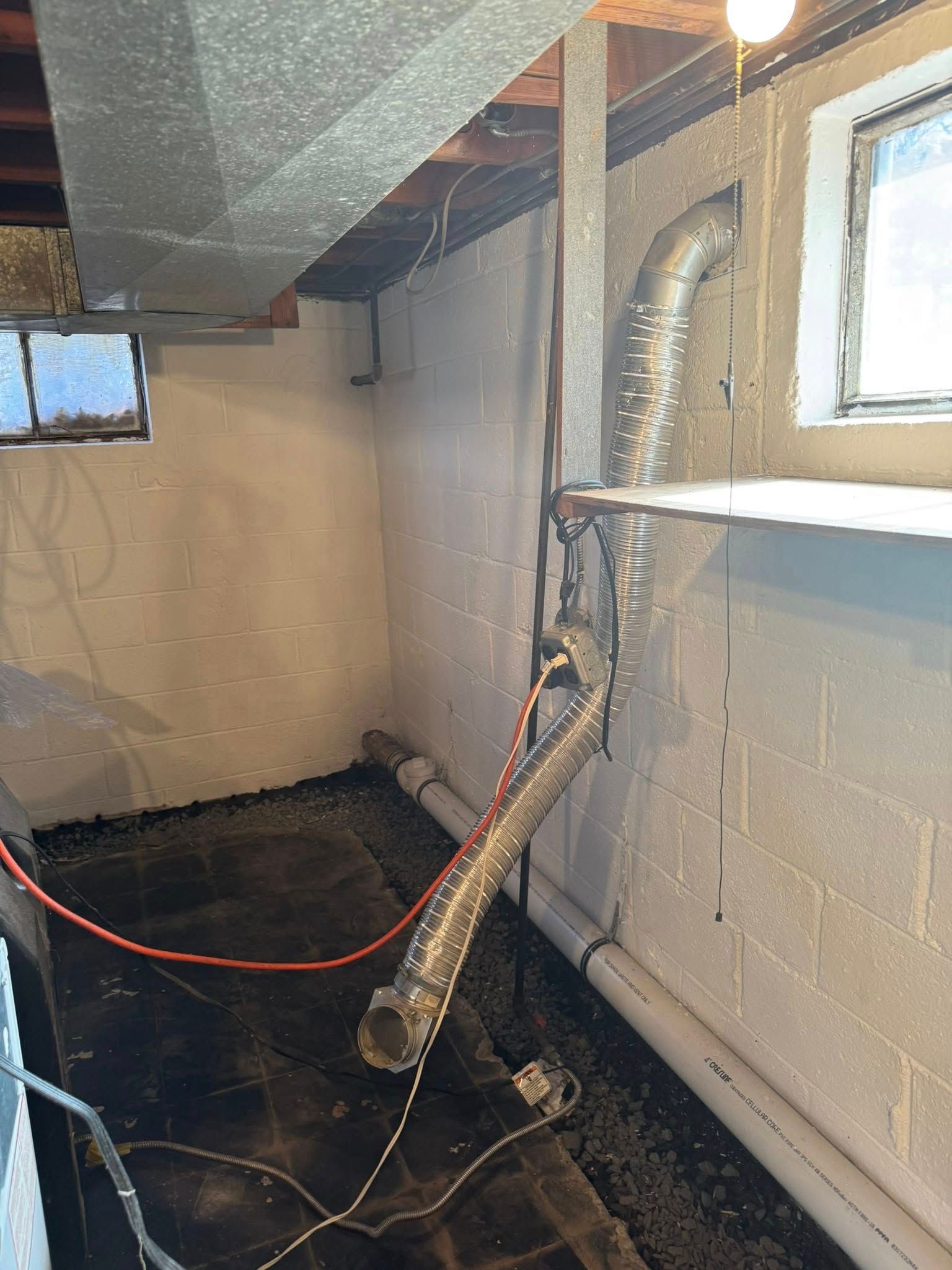 A section of drywall removed to reveal a large vertical crack in the concrete wall, with exposed wood framing and a yellow electrical wire.