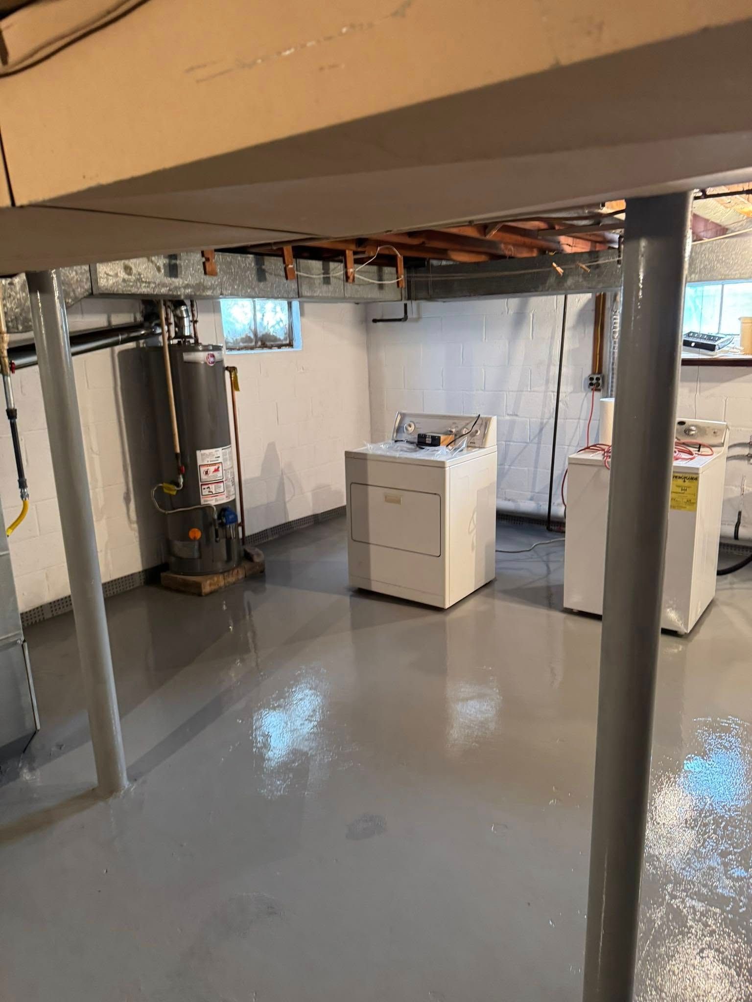A basement with a washer and dryer and a water heater.