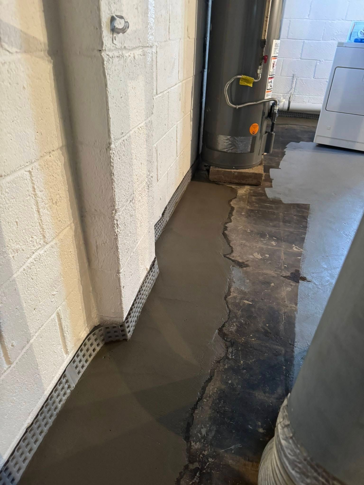 A concrete floor in a basement next to a water heater.