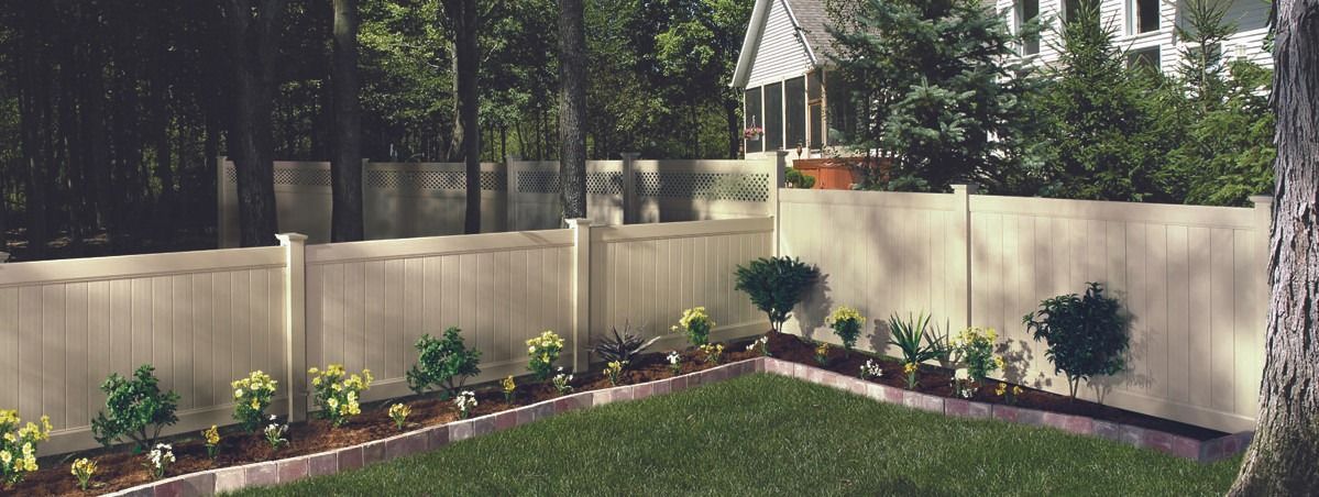 A backyard with a white fence and a lush green lawn