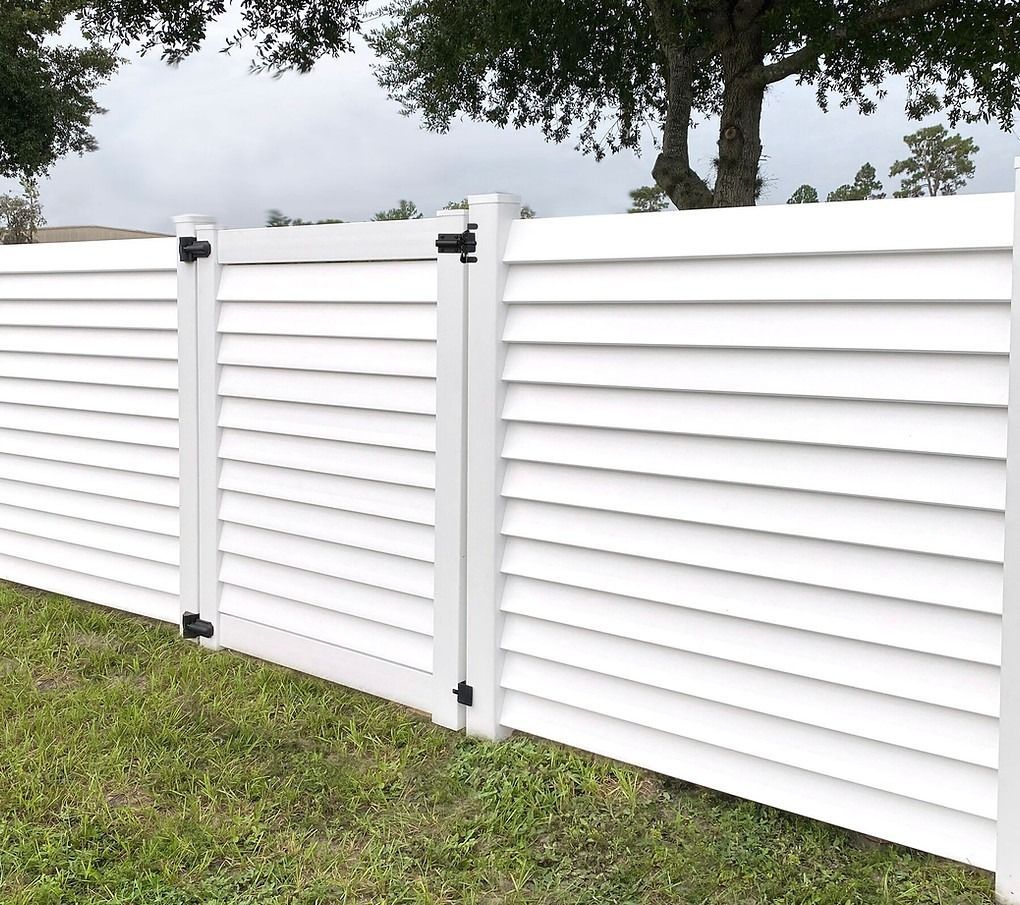 A white fence with a gate is sitting in the grass