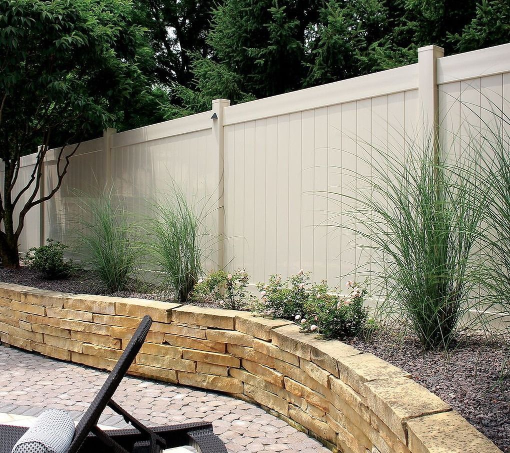 A white fence with a brick wall behind it