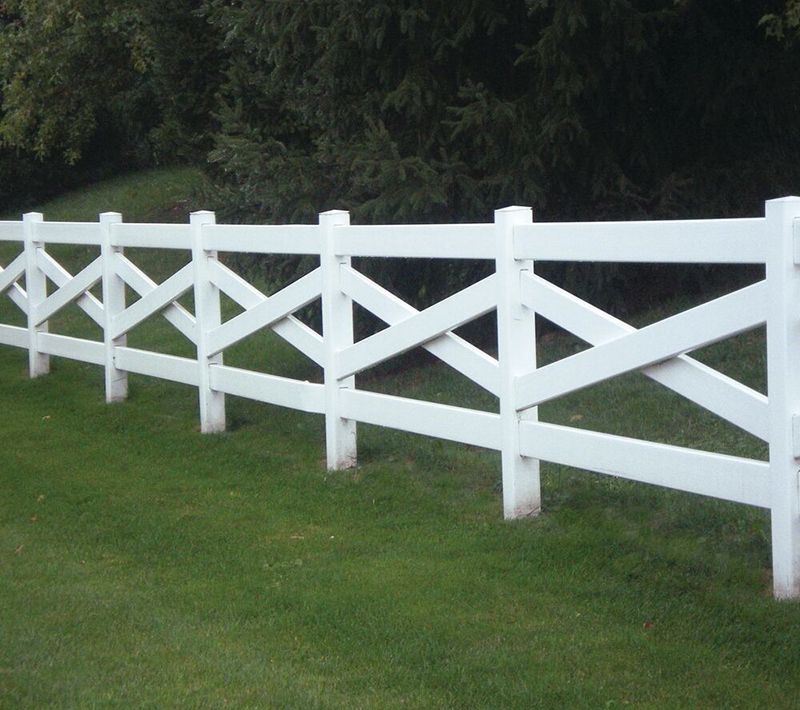 A white fence surrounds a lush green field