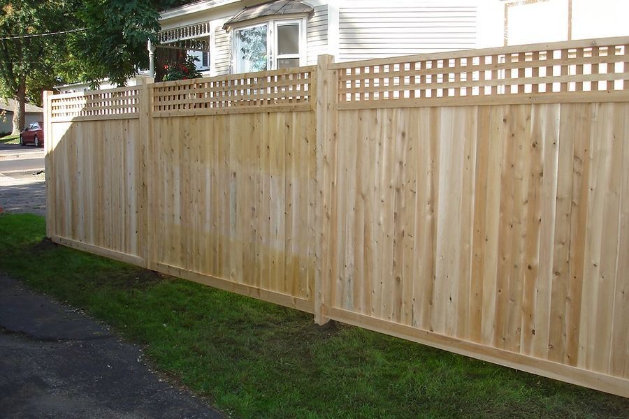 A wooden fence with a lattice top is in front of a house
