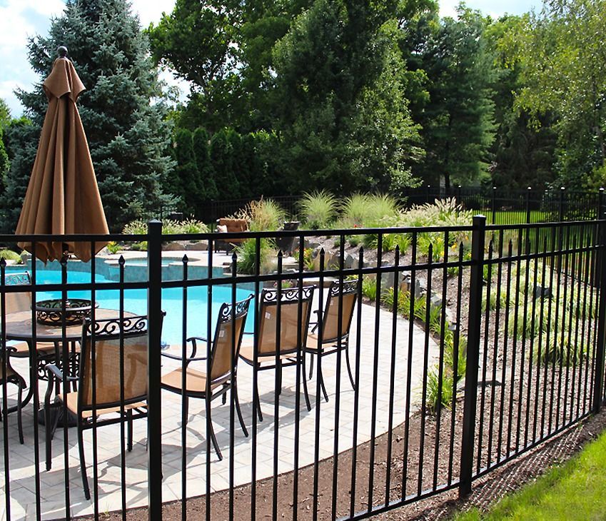 A black fence surrounds a patio area with chairs and umbrellas