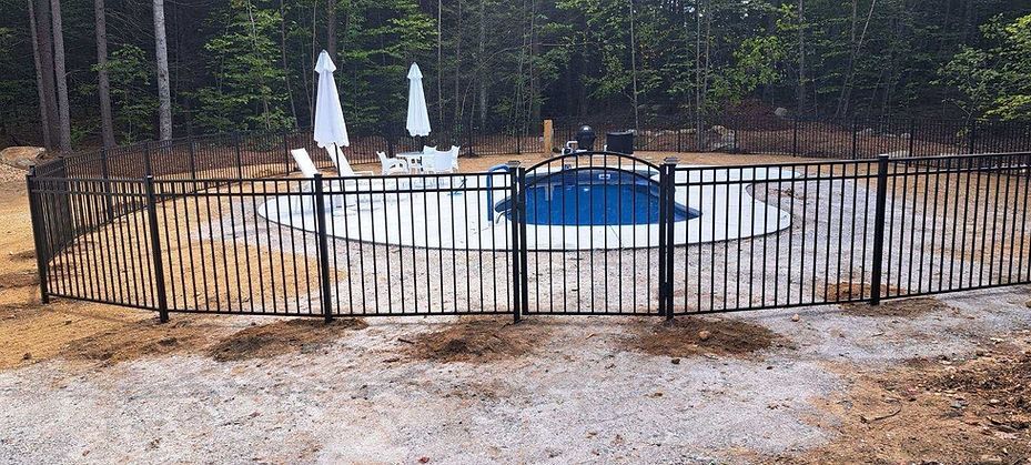 A fence surrounds a swimming pool in a backyard