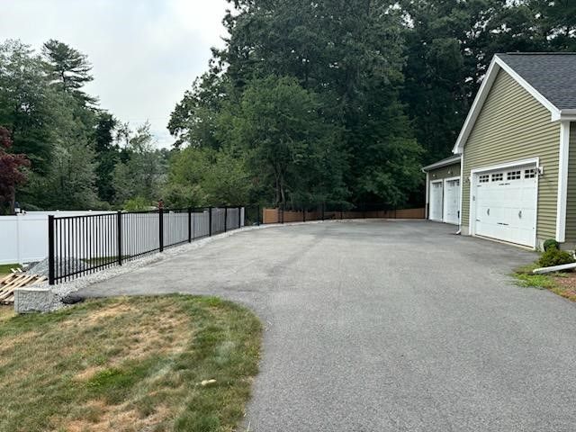 A driveway leading to a house with a garage and a fence
