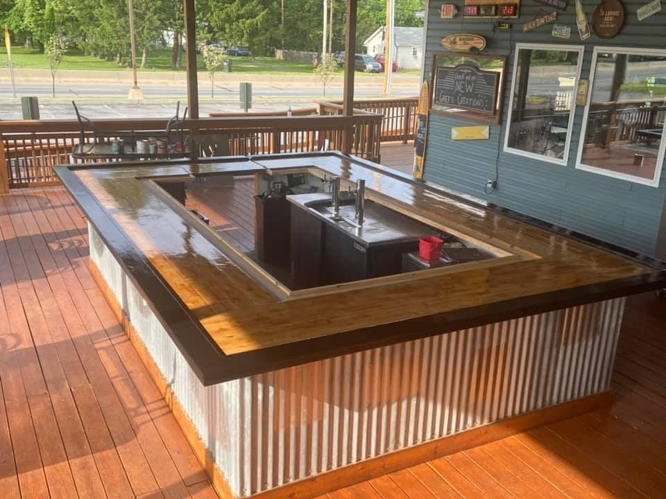 Outdoor bar with a wood top and corrugated metal base; beer taps visible.