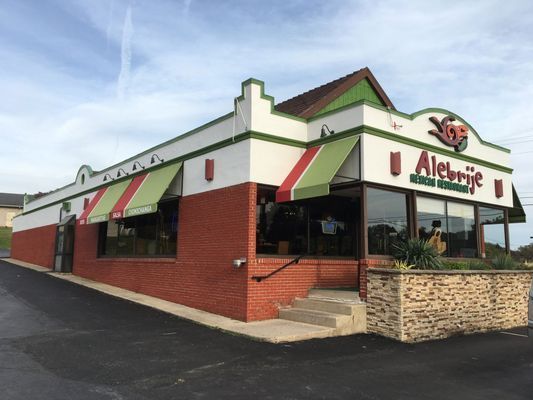 Exterior of Alebrije Mexican Restaurant, red brick and white building with green and red awnings.