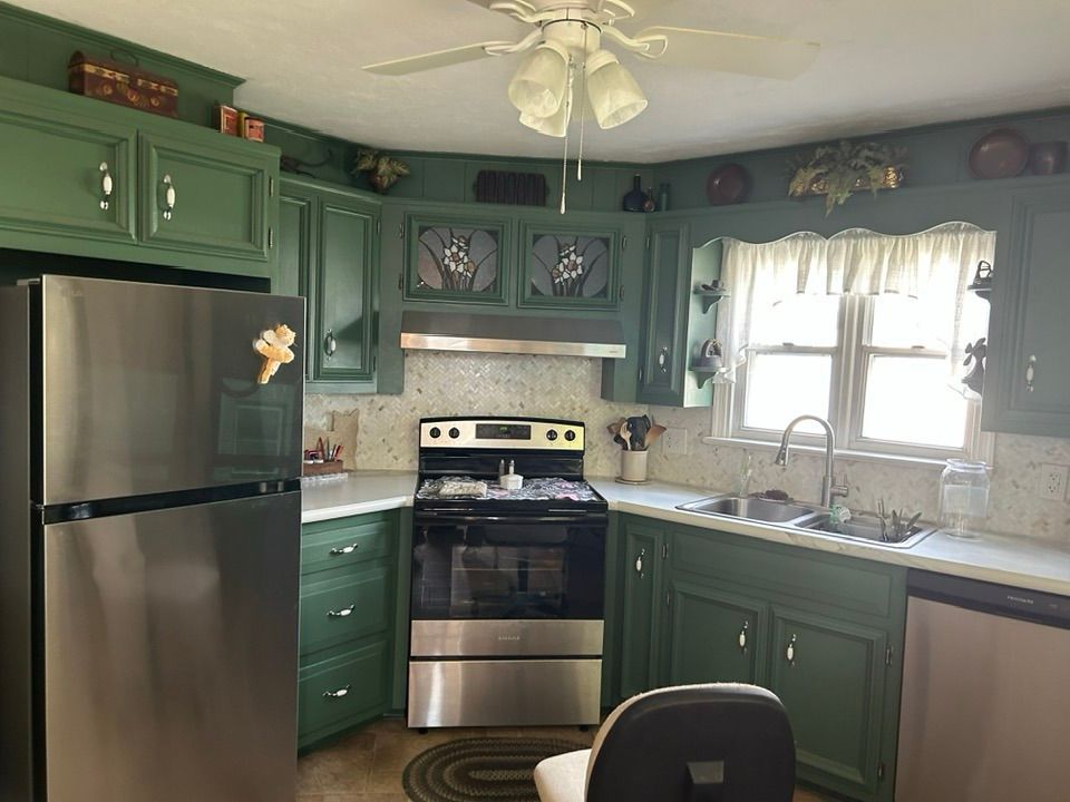 Green-painted kitchen with stainless steel appliances, white countertops, and a ceiling fan.