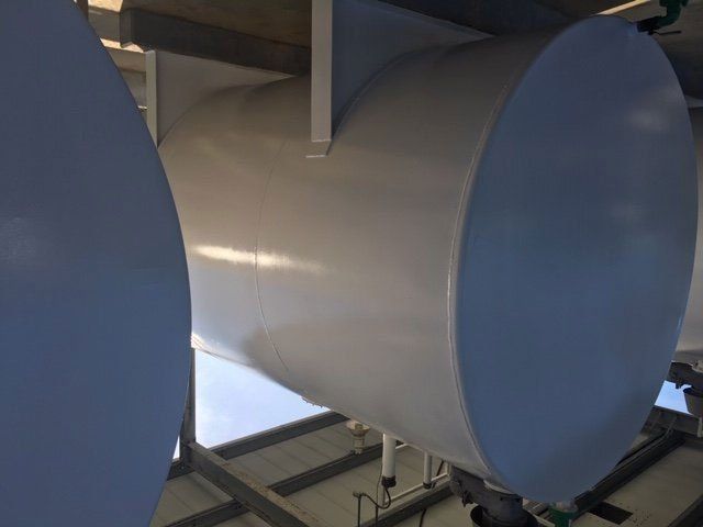 White cylindrical ductwork installed in industrial setting.