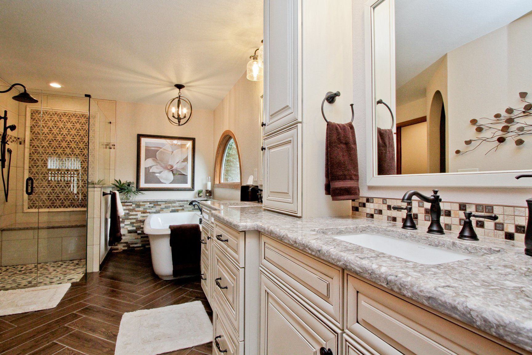 A bathroom with a tub , sink , mirror and cabinets.