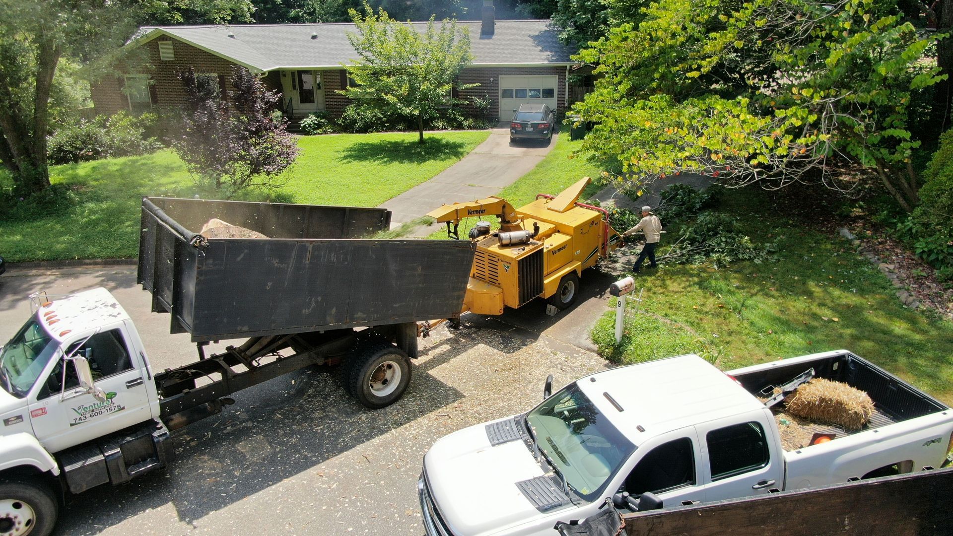 Two dump trucks are parked in front of a house.