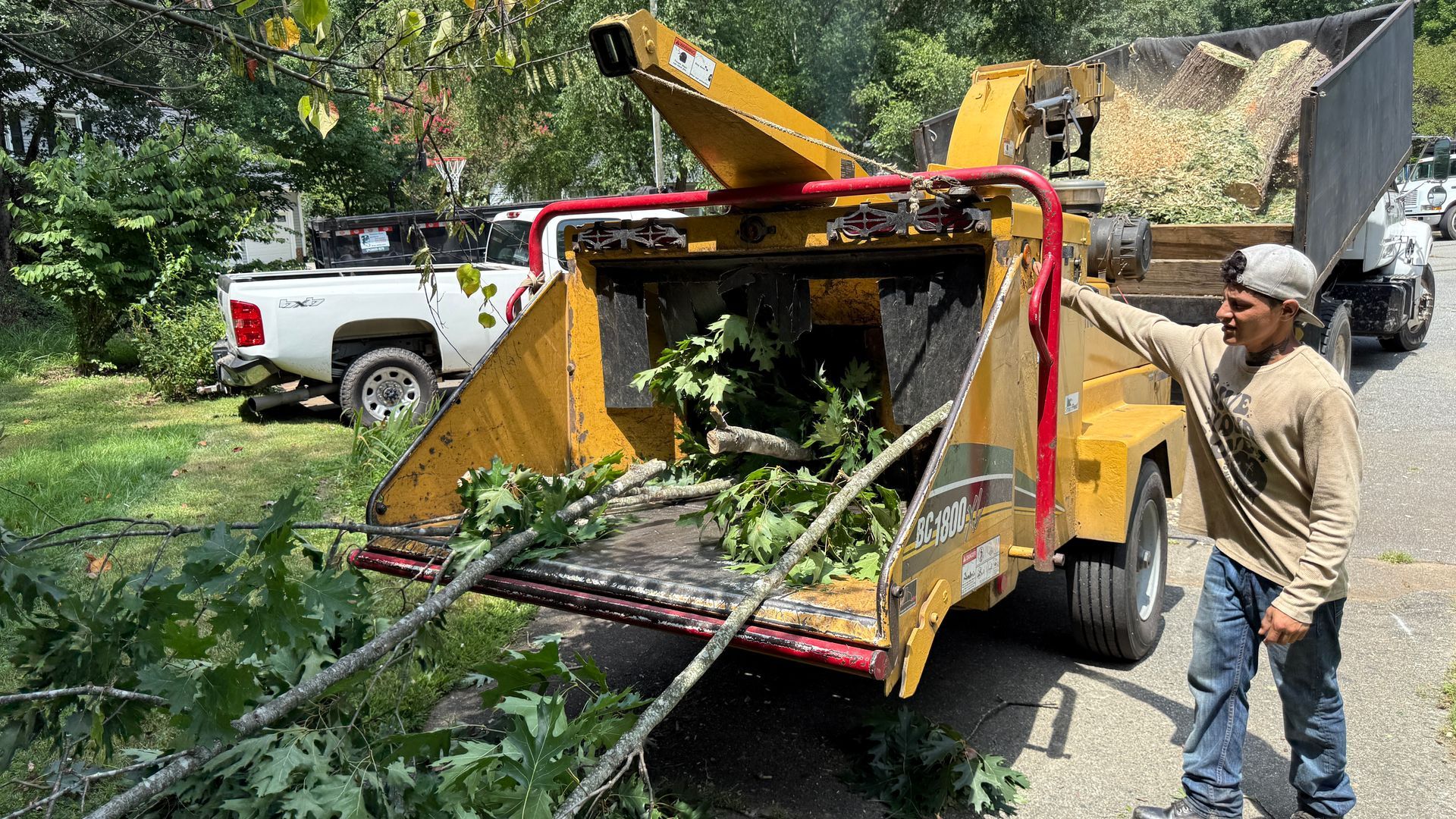 A man is standing next to a tree chipper.