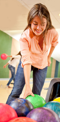 Woman picking up a bowling ball