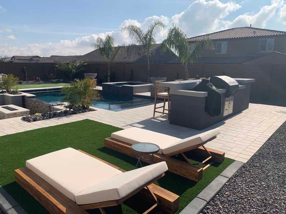 A backyard with a swimming pool , lawn chairs , and a grill.