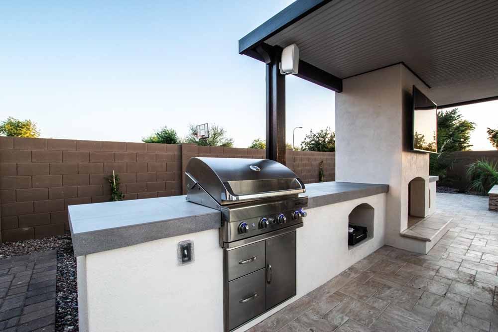 An outdoor kitchen with a grill and a fireplace.