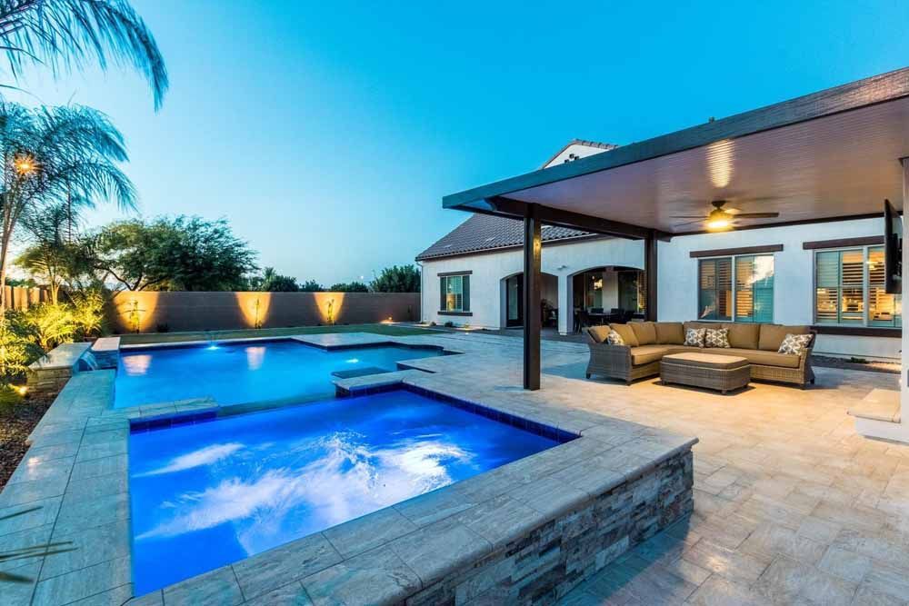 There is a large swimming pool in the backyard of a house.