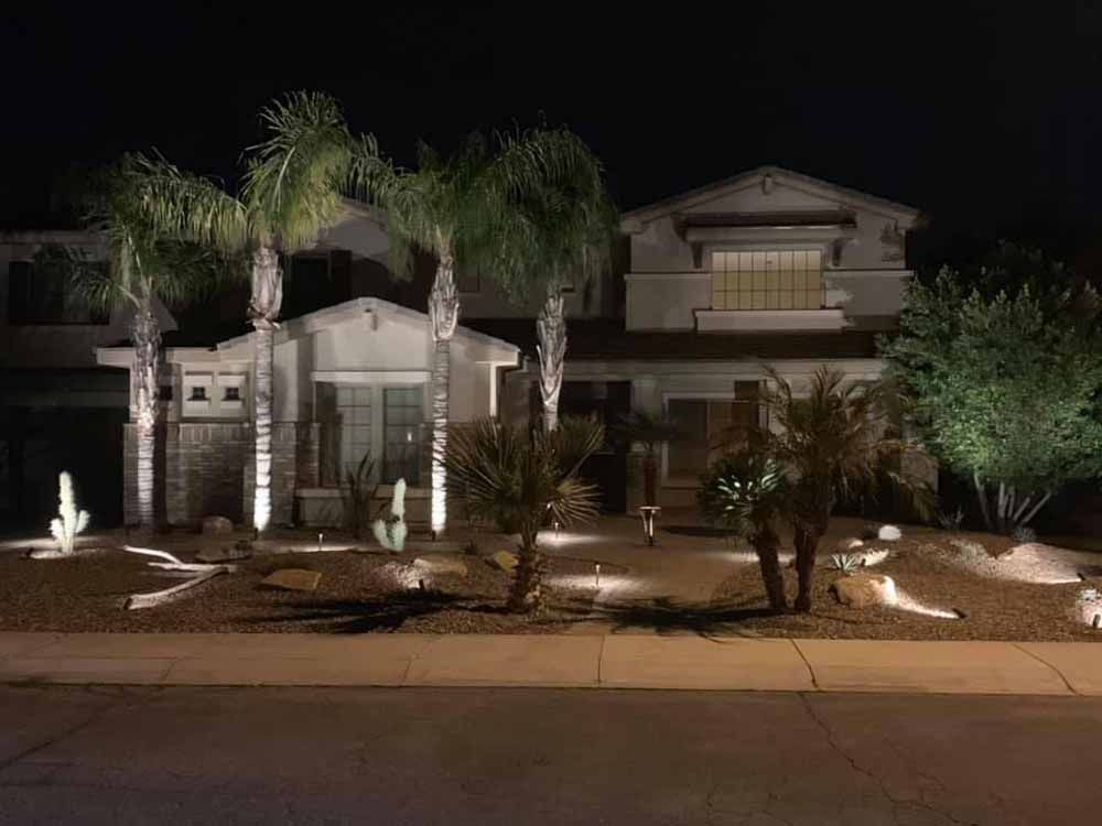 A house with palm trees in front of it is lit up at night.