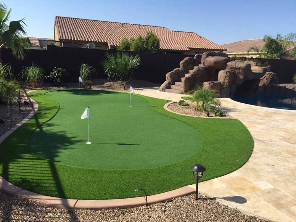 A putting green in a backyard with a house in the background