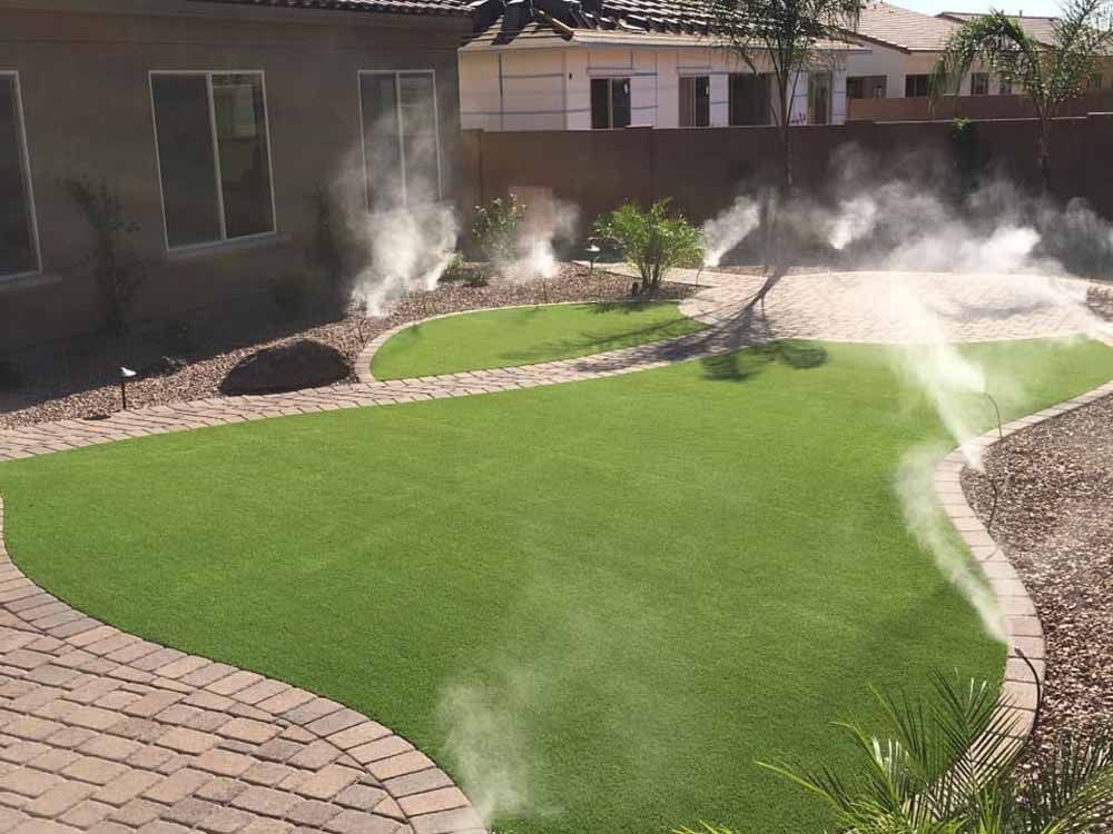 A sprinkler is spraying water on a lush green lawn.