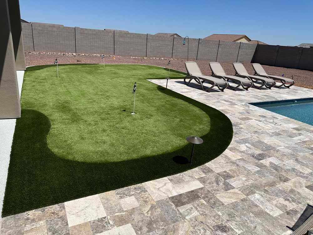 A backyard with a putting green and a swimming pool.
