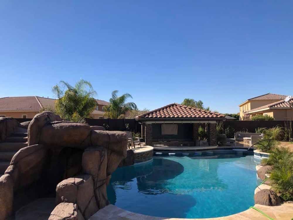 There is a large swimming pool in the backyard of a house.