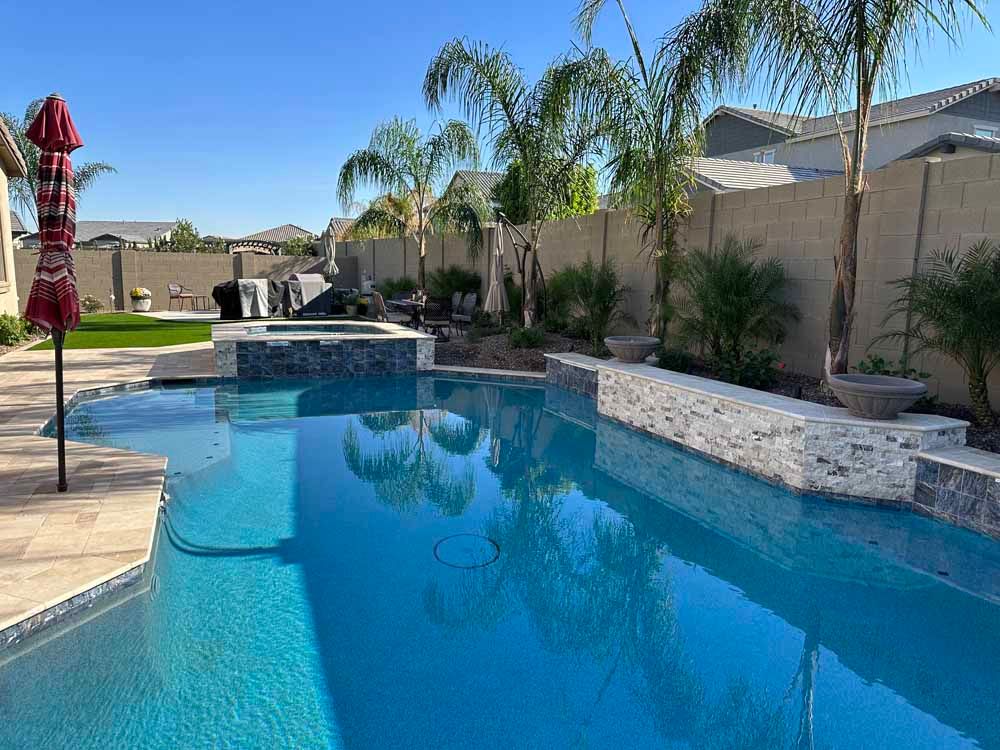 There is a large swimming pool in the backyard of a house.