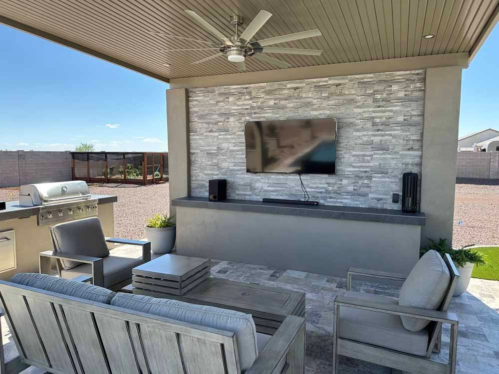 A patio with a couch , chairs , table and television.
