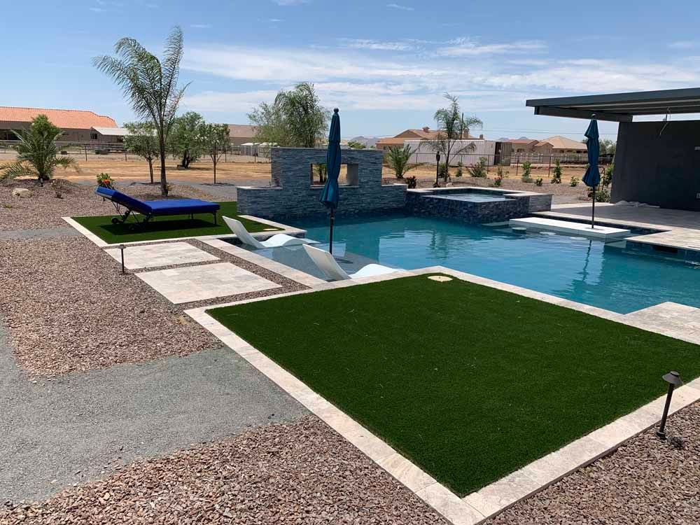 A large swimming pool surrounded by a lush green lawn.