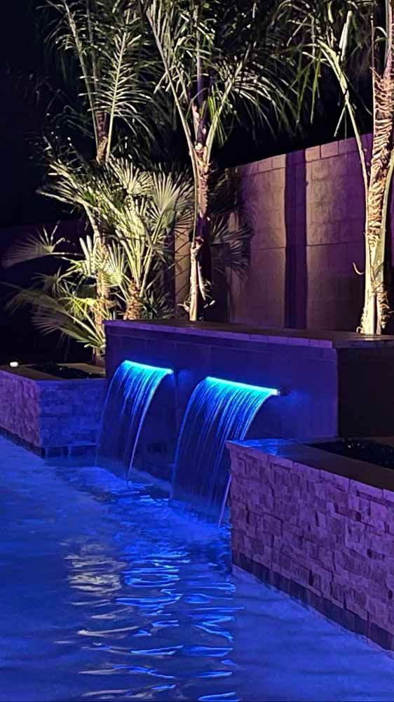 There is a waterfall in the middle of the pool at night.