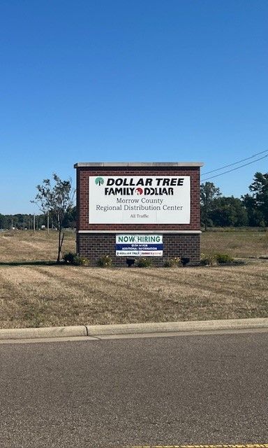 A brick sign for the Dollar Tree Family Dollar Regional Distribution Center in a field under a clear blue sky.