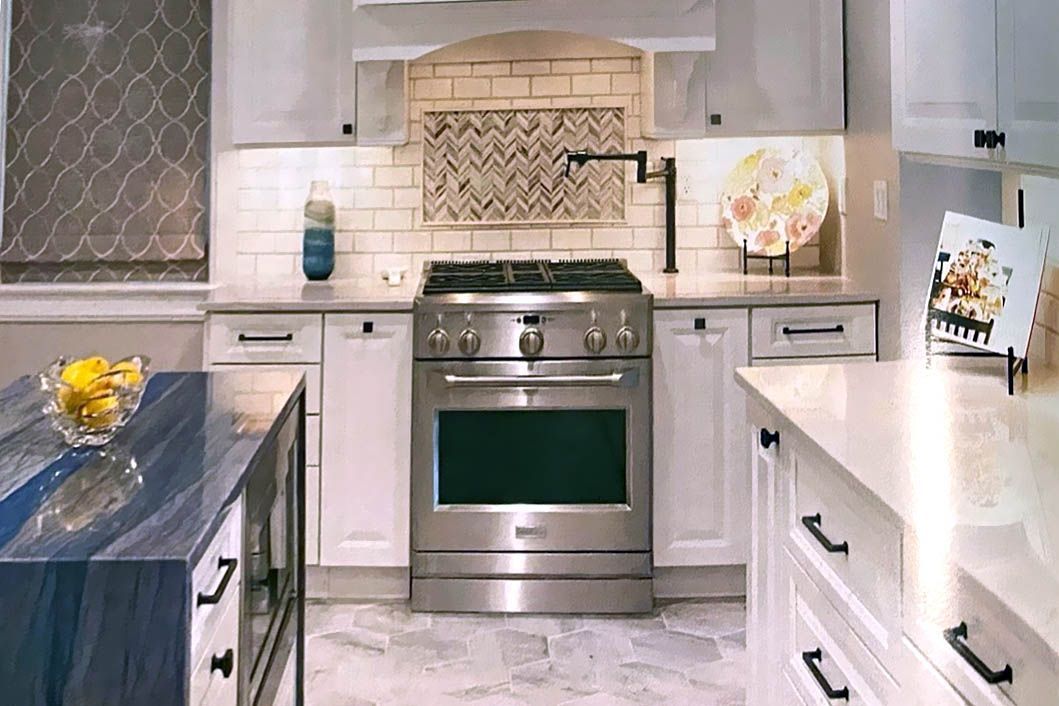 Modern kitchen with stainless steel oven, white cabinets, blue island, and patterned backsplash.