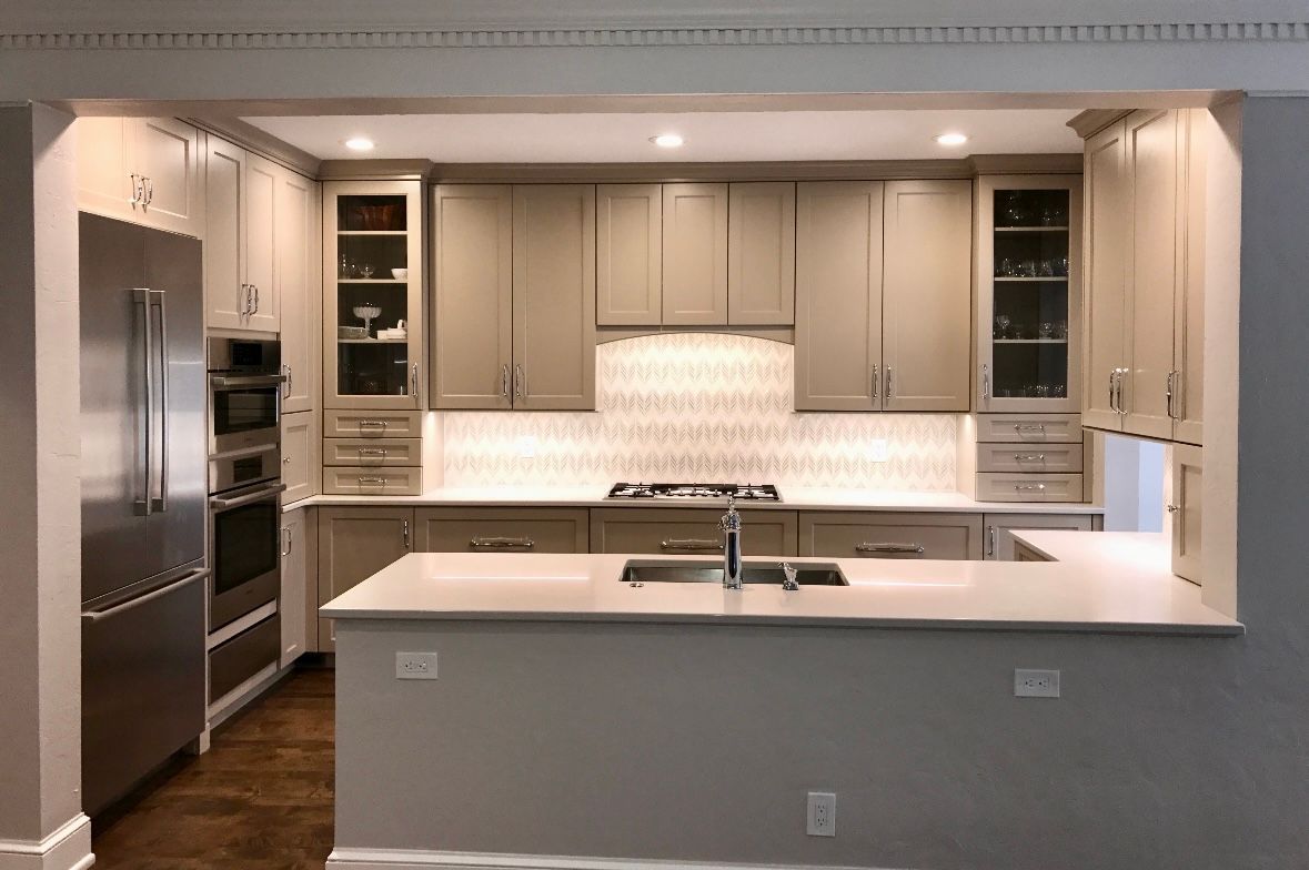 Modern kitchen with light cabinets, stainless steel appliances, and white countertops.