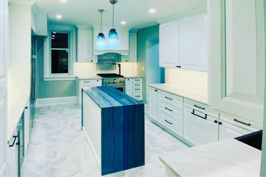 White kitchen with blue island and accent lighting; cabinets, island, stove, and window.