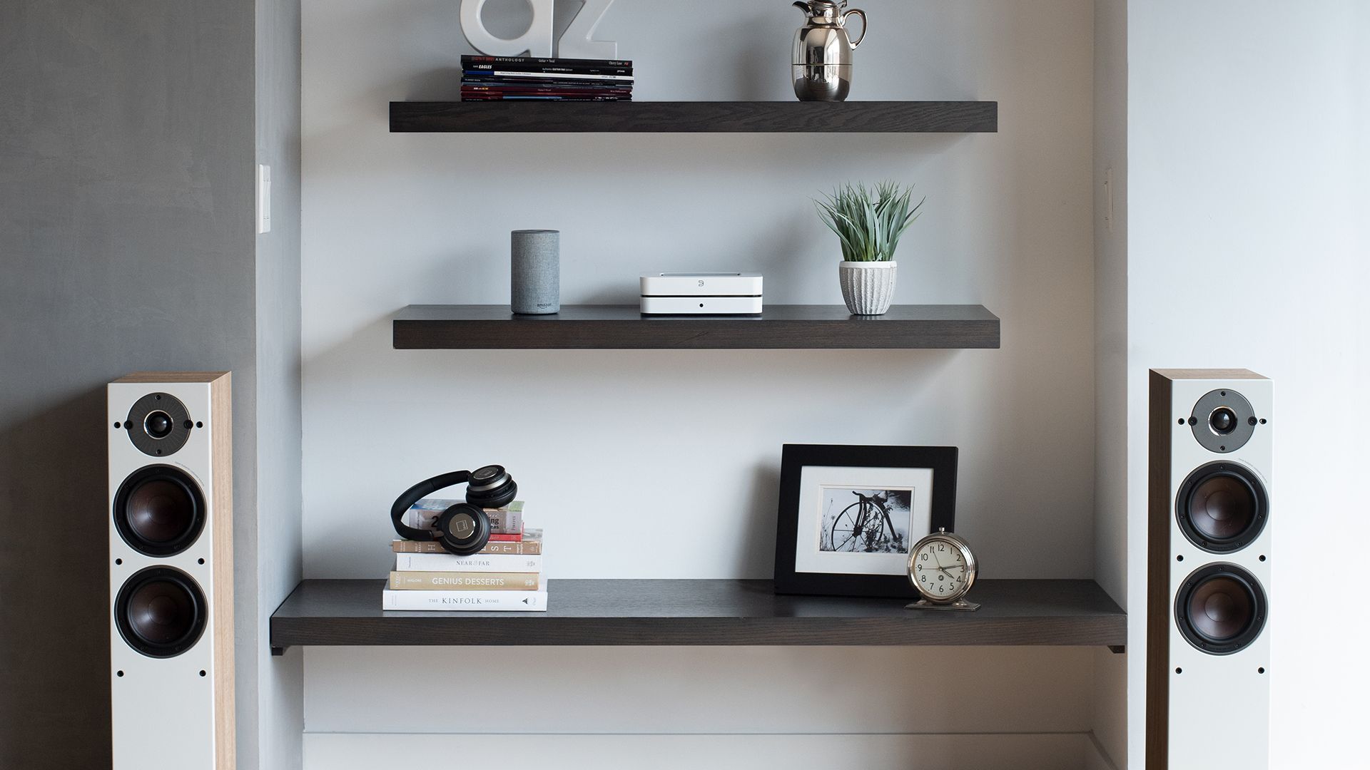 A living room with two speakers and a shelf with a picture on it.