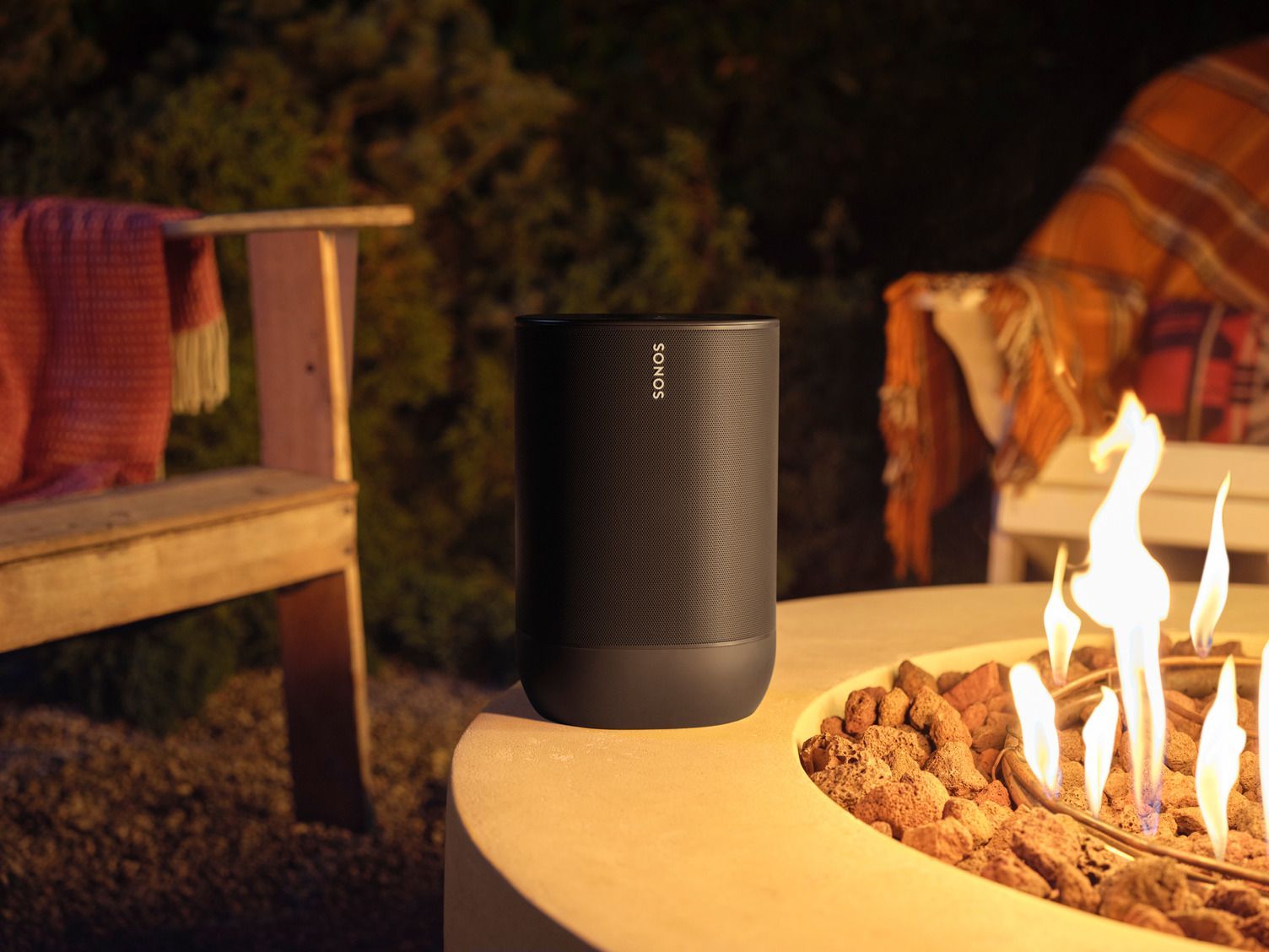 A speaker is sitting on a table next to a fire pit.