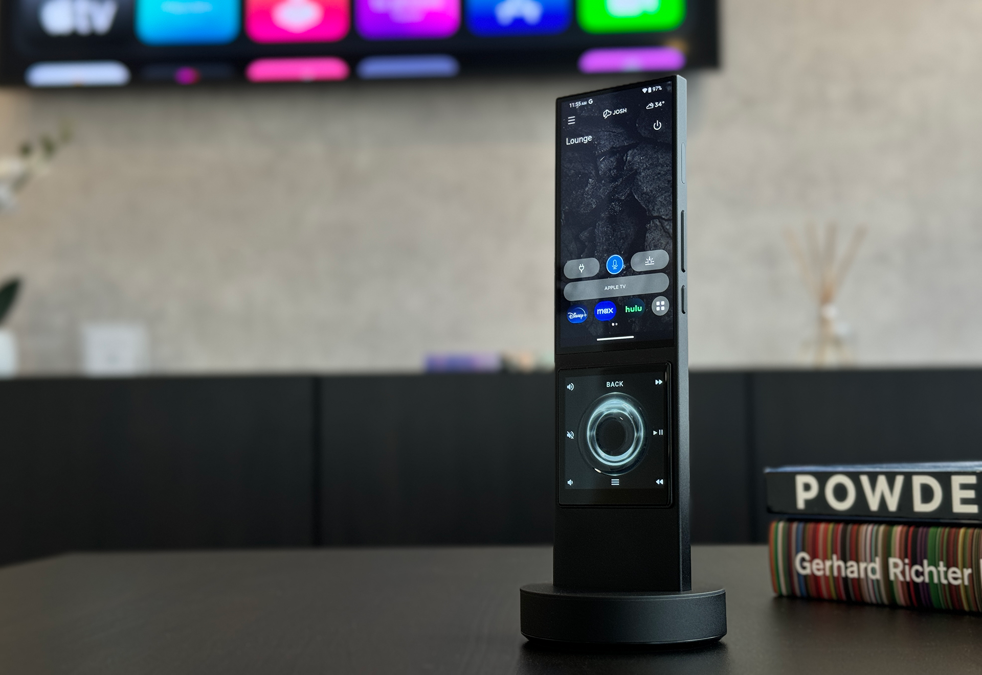 A remote control is sitting on a table next to a book called powde