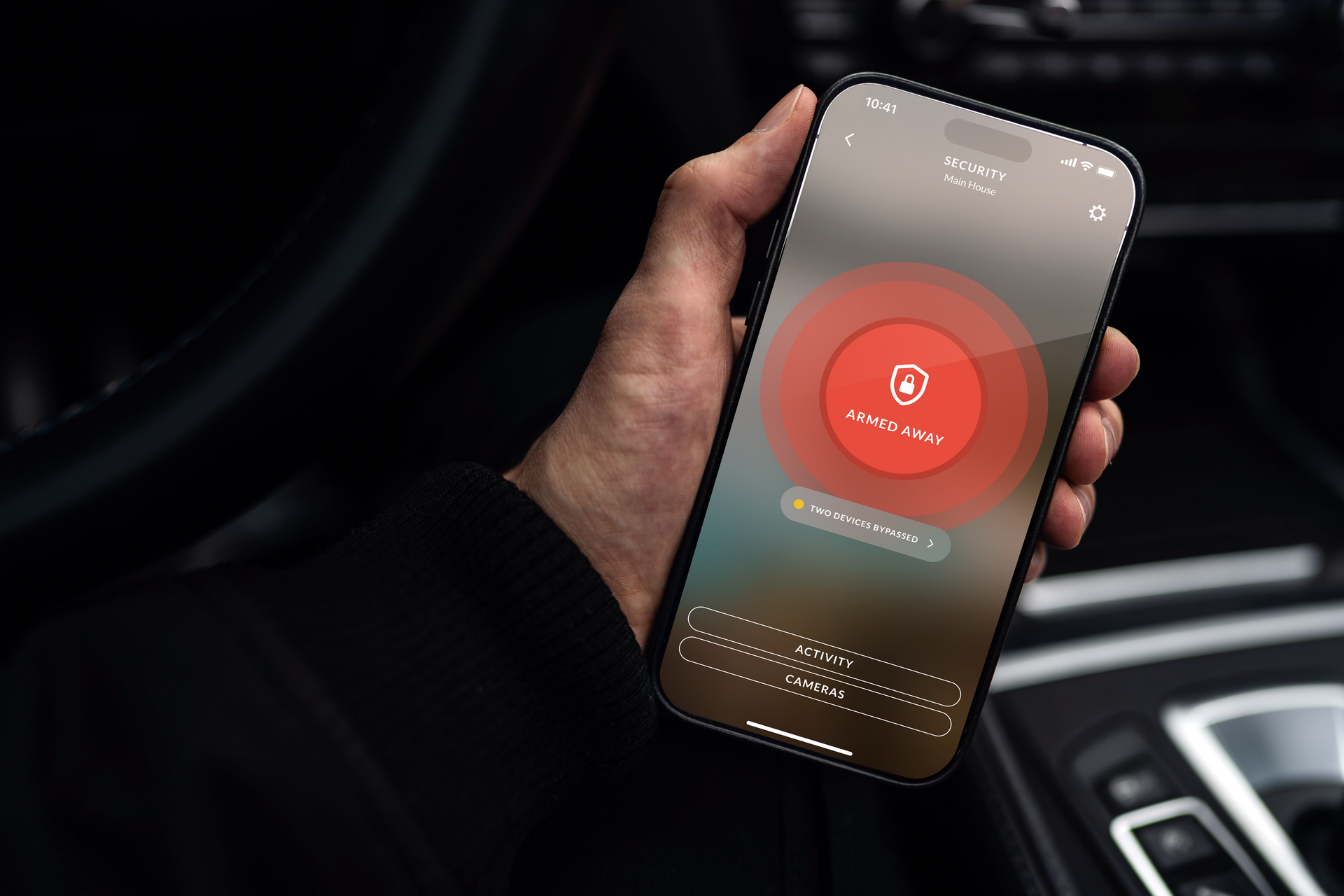 A person is holding a cell phone in their hand in a car.