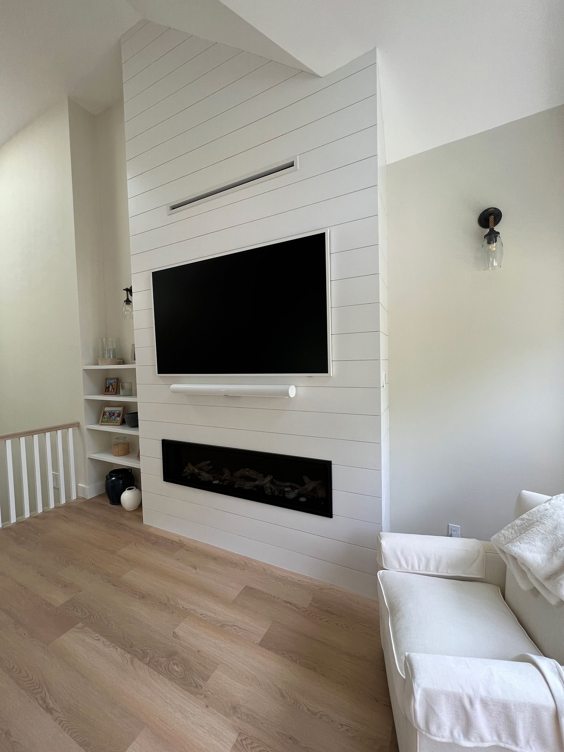 A living room with a fireplace and a flat-screen tv on the wall.