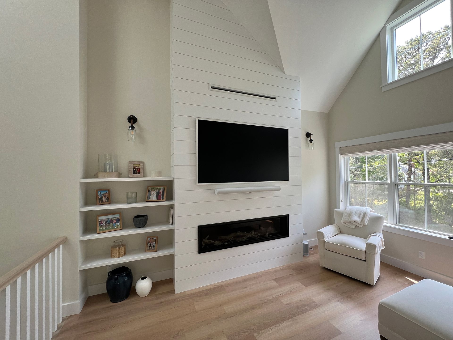 A living room with a fireplace and a flat-screen tv on the wall.