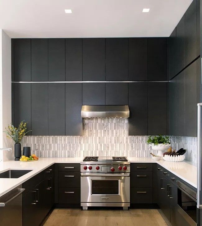A kitchen with black cabinets and stainless steel appliances