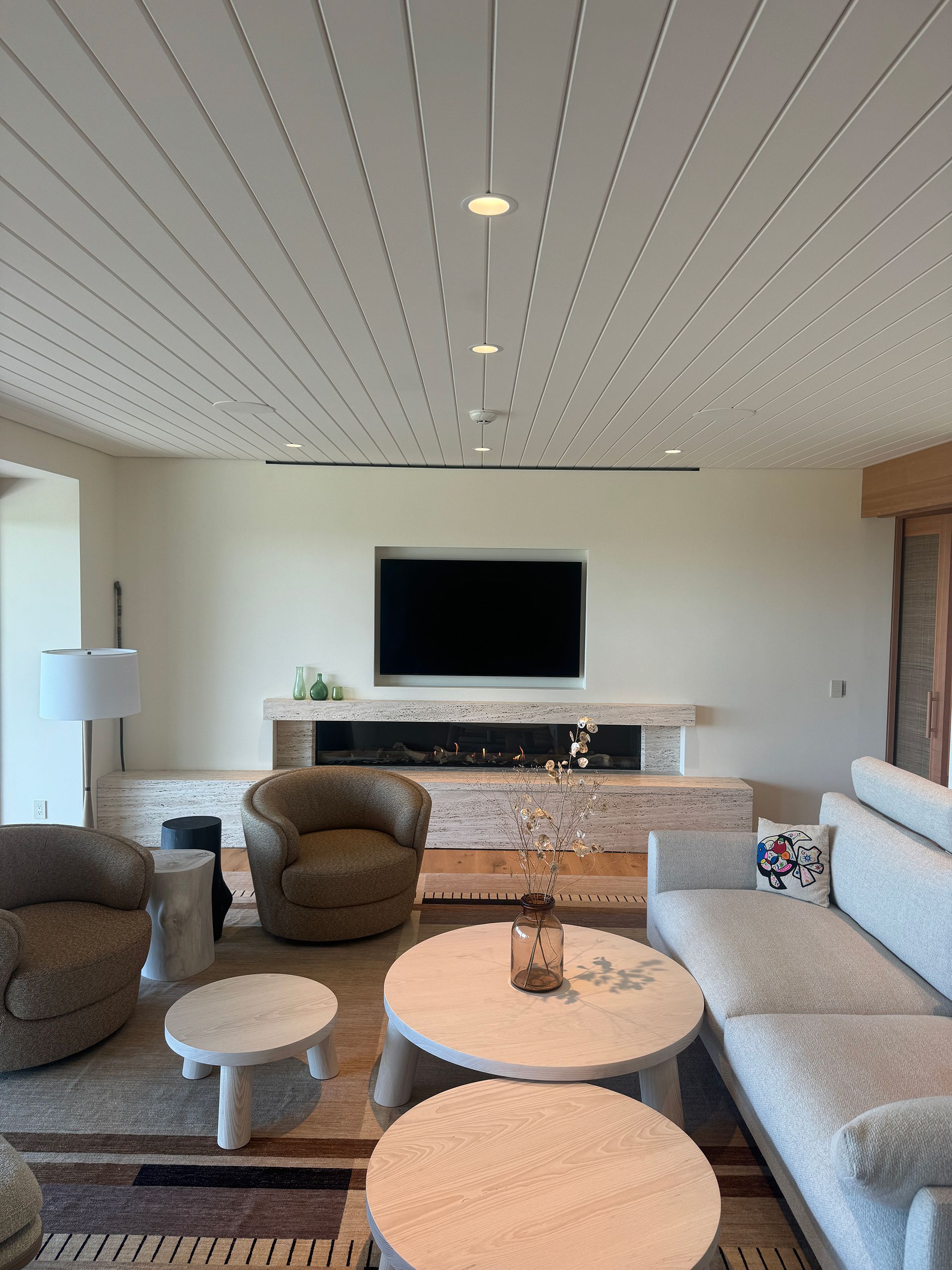 A living room with a couch, chairs, tables, and a flat-screen tv.