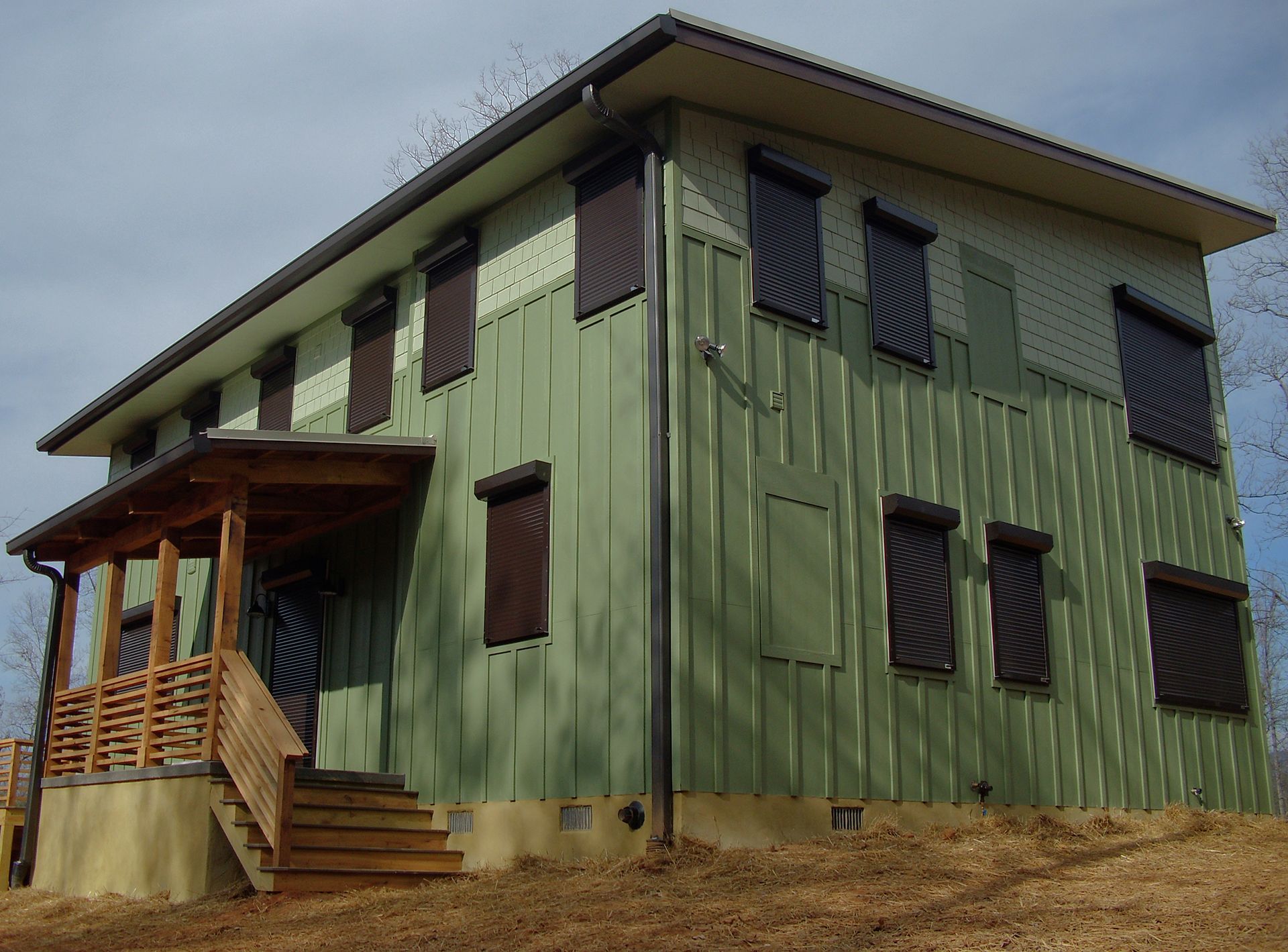 A green house with brown shutters on the windows