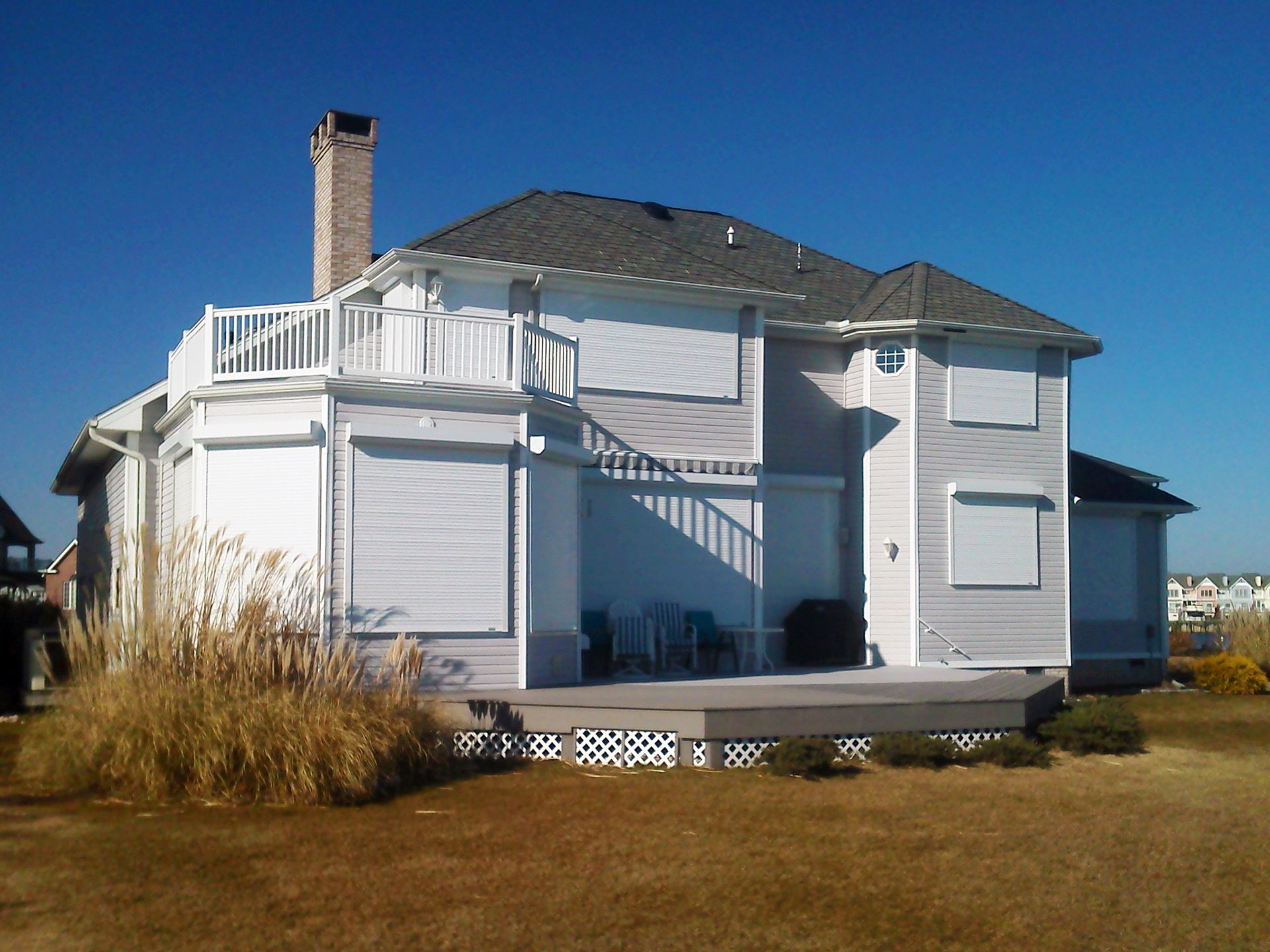 A white house with a balcony and shutters on the windows