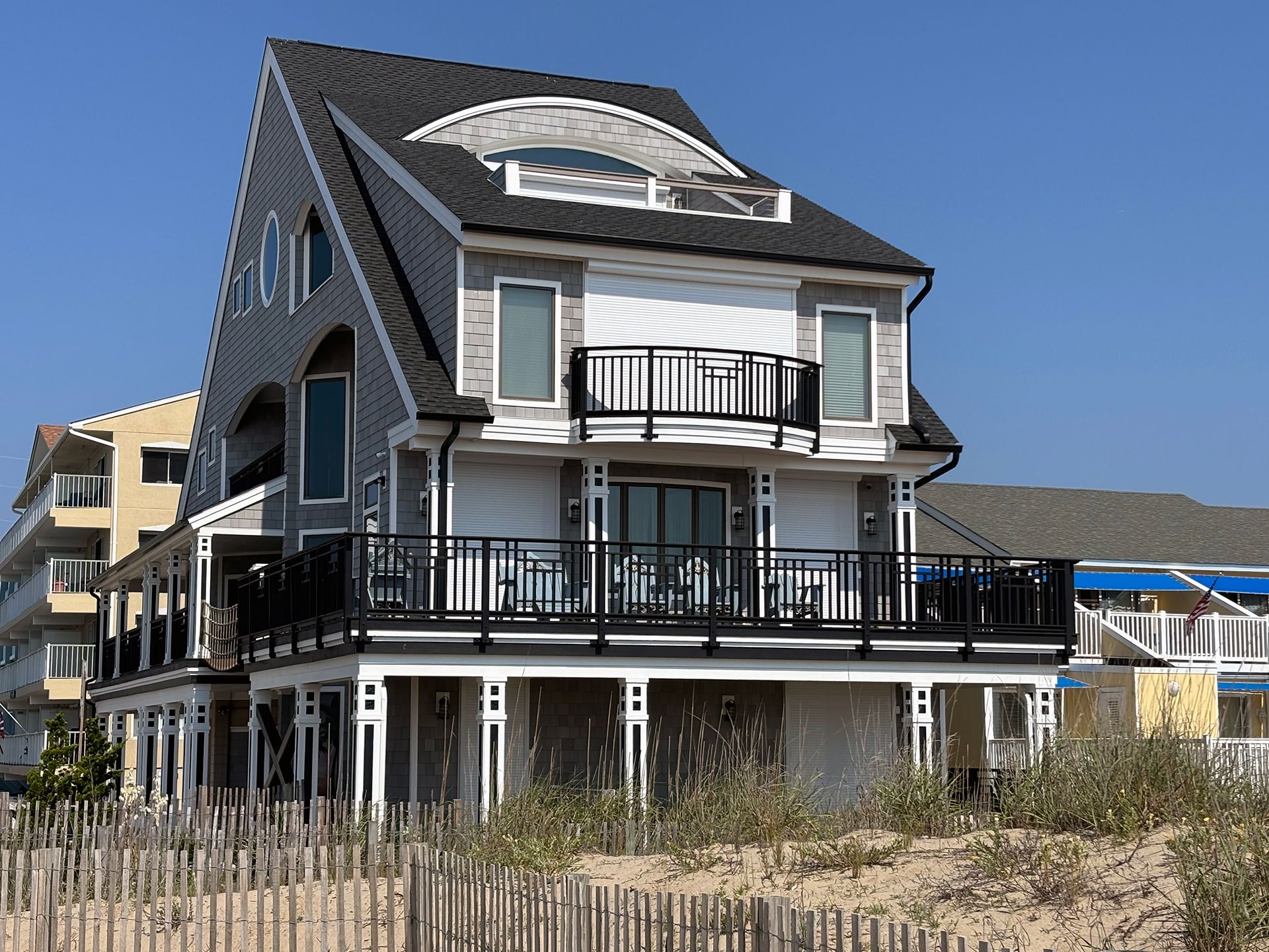 A large house with a balcony is sitting on top of a sand dune