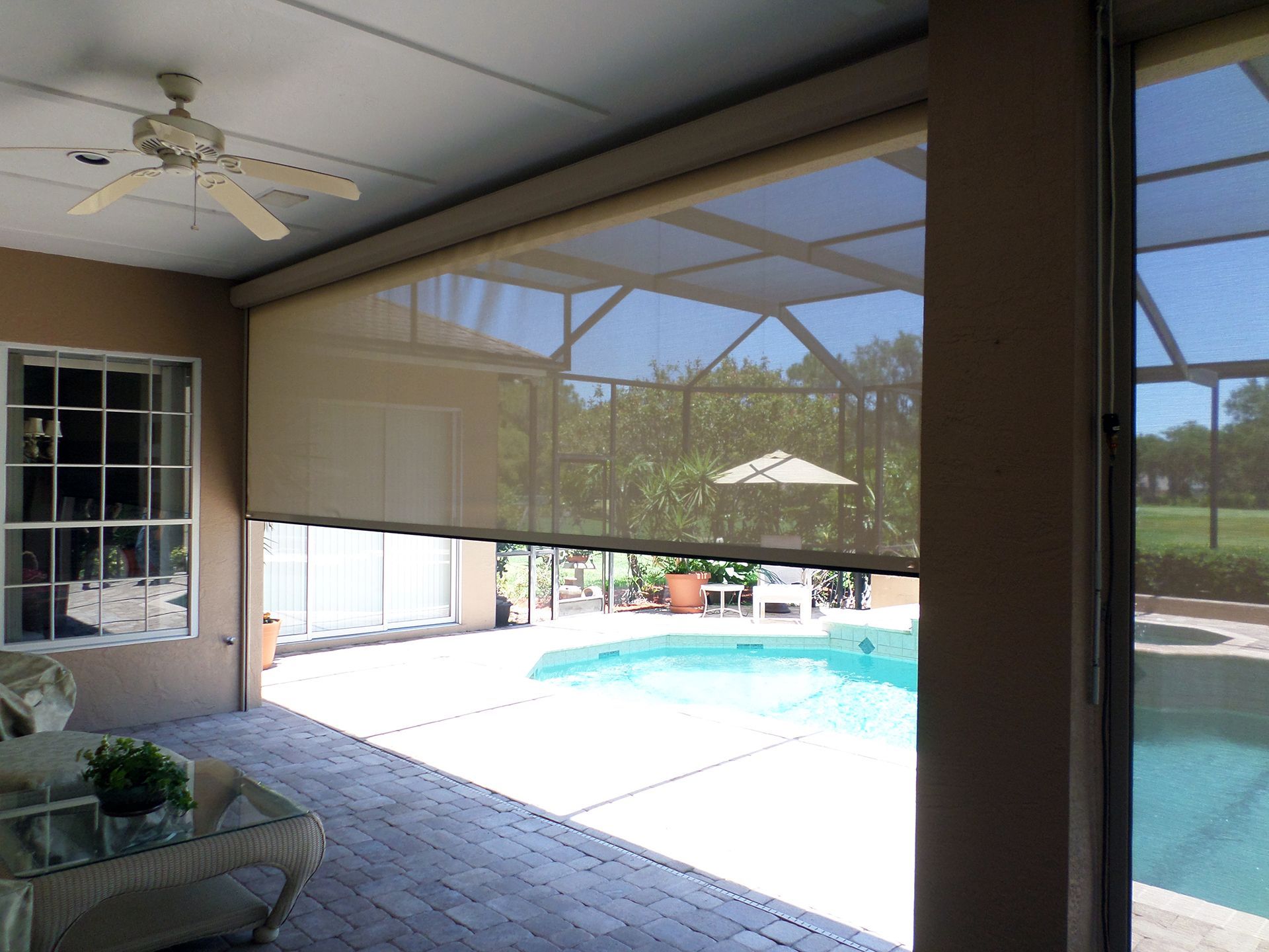 A screened in porch with a swimming pool in the background