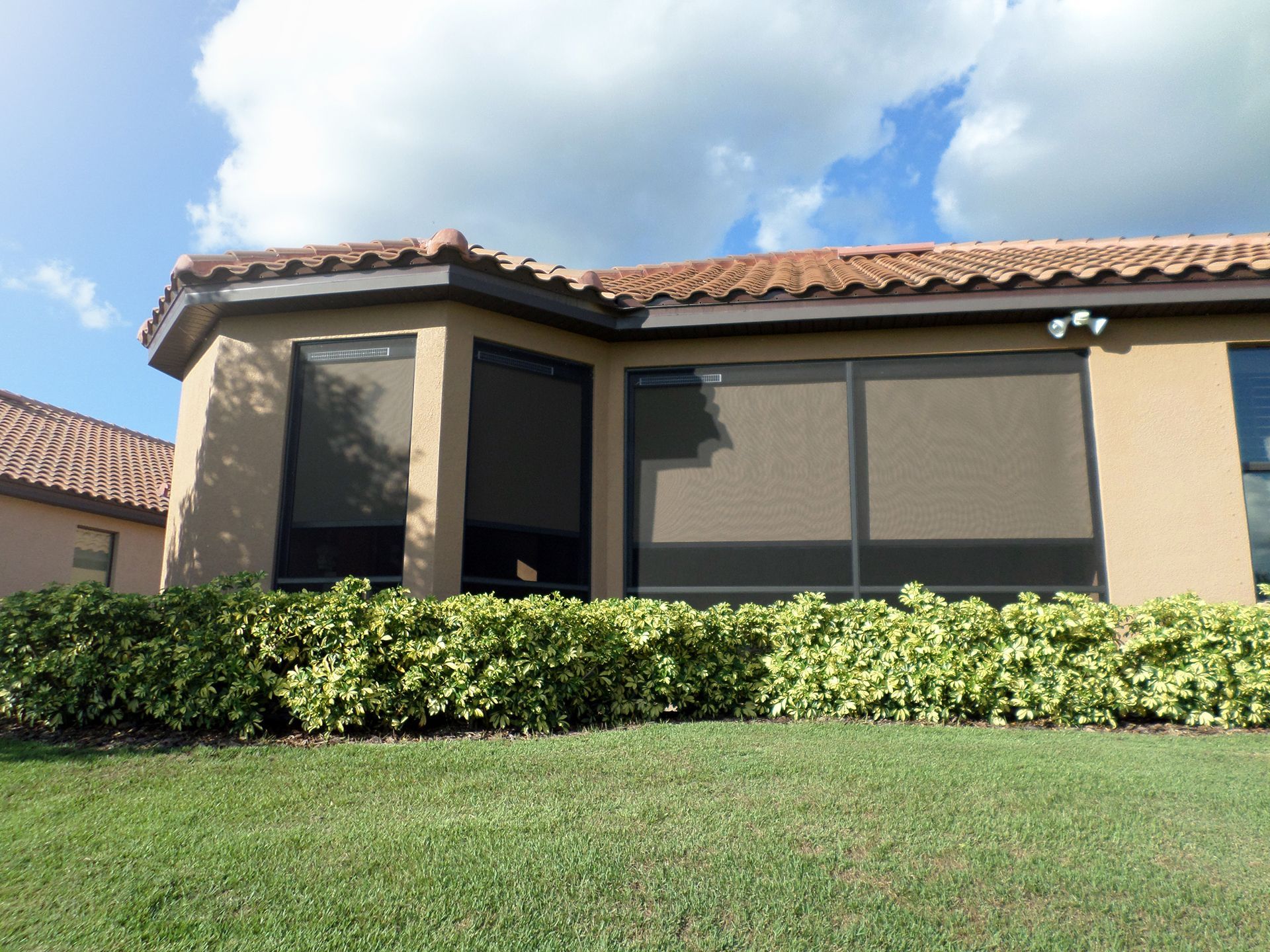A house with a screened in porch and a lawn in front of it
