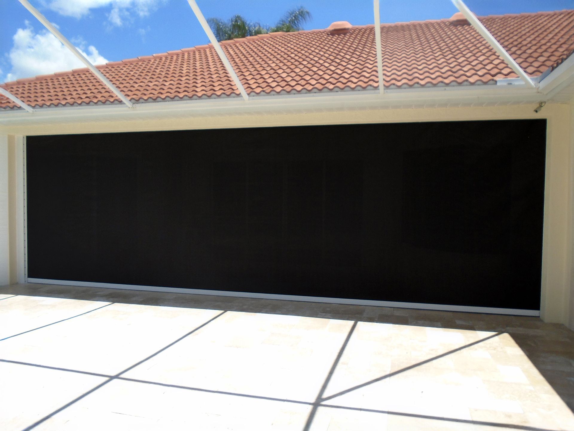 A large black garage door with black screen