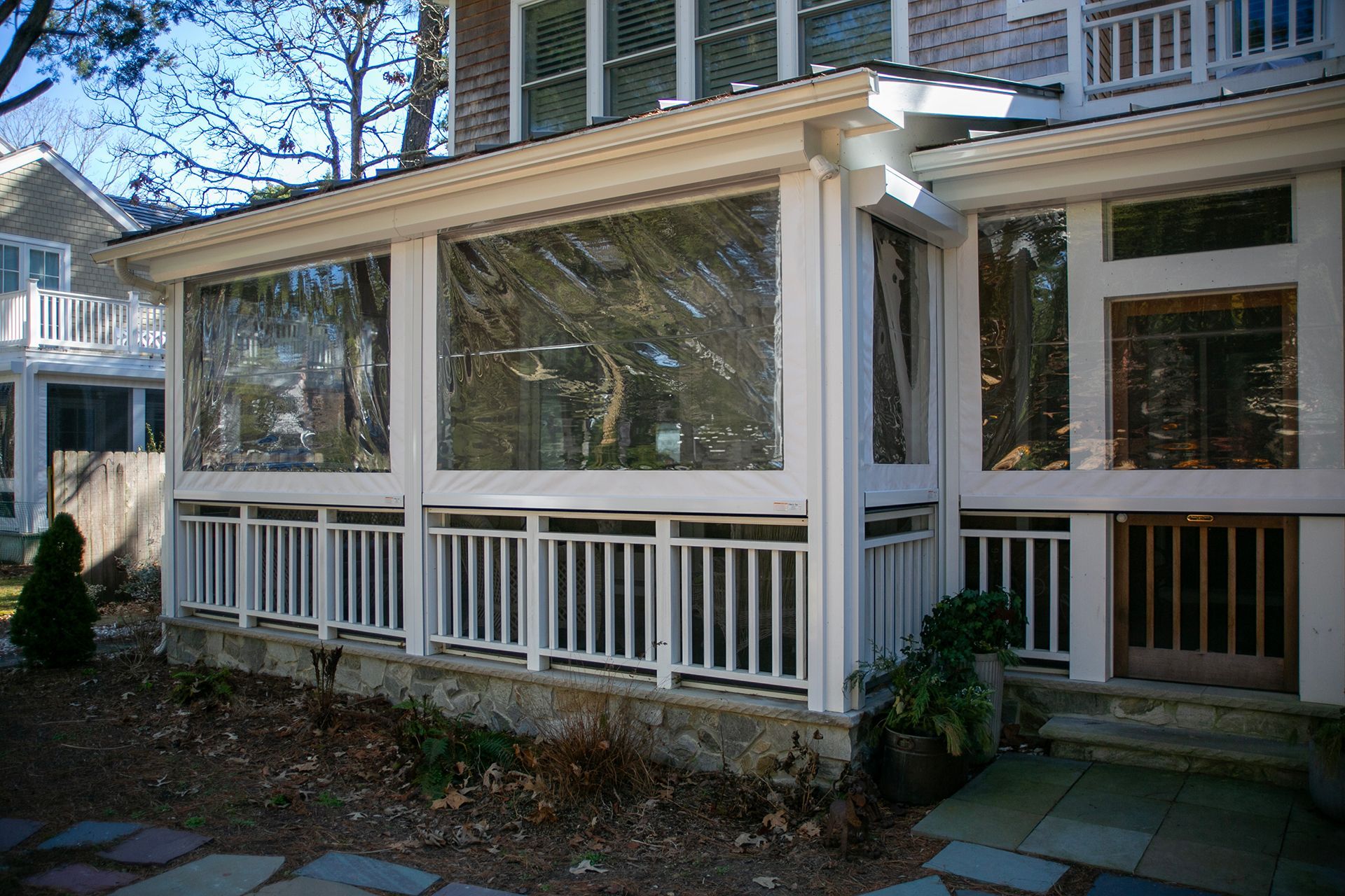 A screened in porch with a white railing and lots of windows